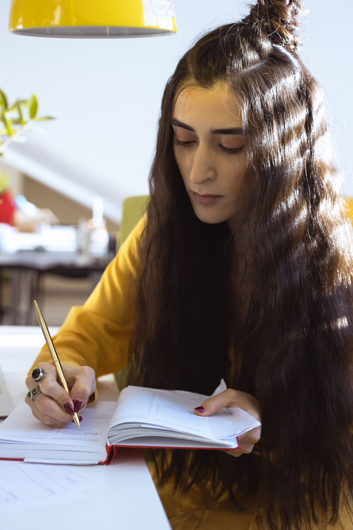 Pessoa escrevendo em um caderno à mesa